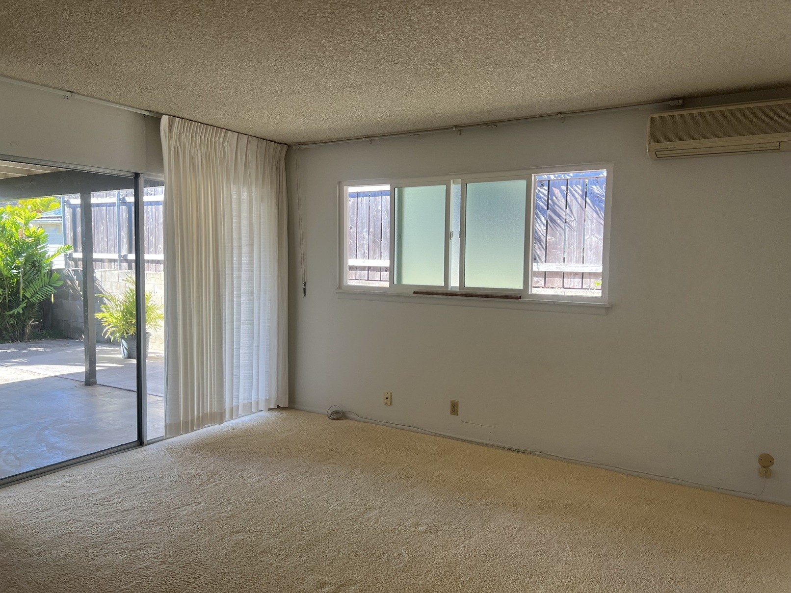 A room with a carpeted floor and a sliding glass door.